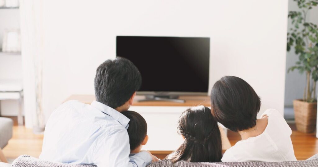 映画情報をイメージ、自宅のテレビで家族で映画を観ている画像